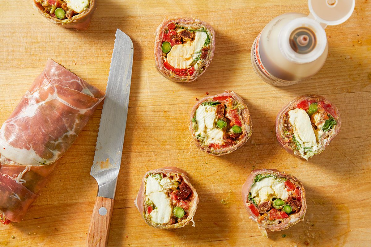 The rolled log is sliced into bite-size rounds using a knife and arranged for serving.