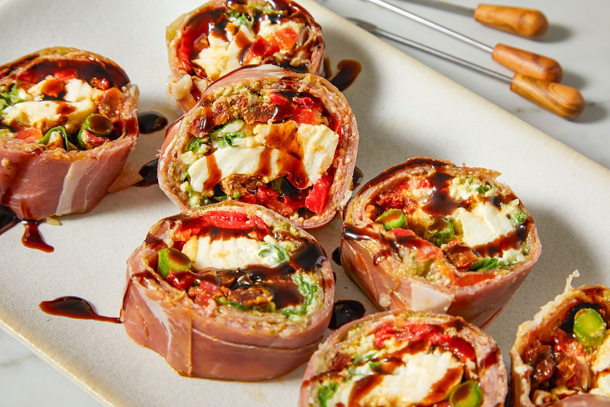 A close-up highlights the layered fillings of burrata, vegetables, and pesto inside each slice.