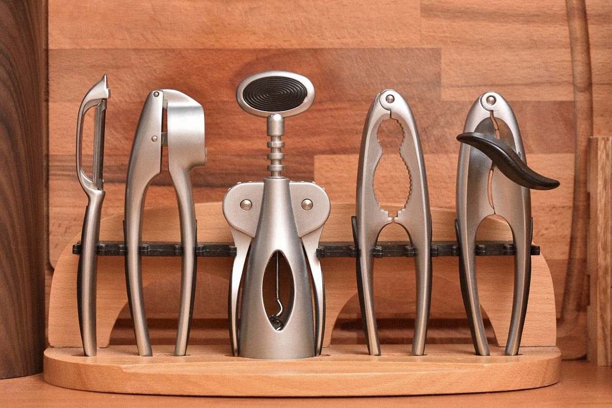 A set of kitchen utensils on a wooden background, garlic press, wine opener, nutcracker, can opener, a knife for cleaning potatoes