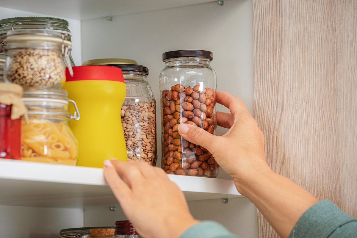 close up of hand reaching for nuts on a kitchen shelf