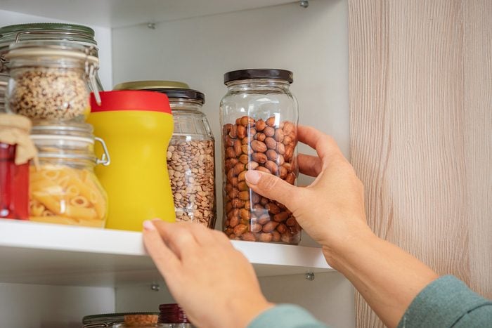 close up of hand reaching for nuts on a kitchen shelf