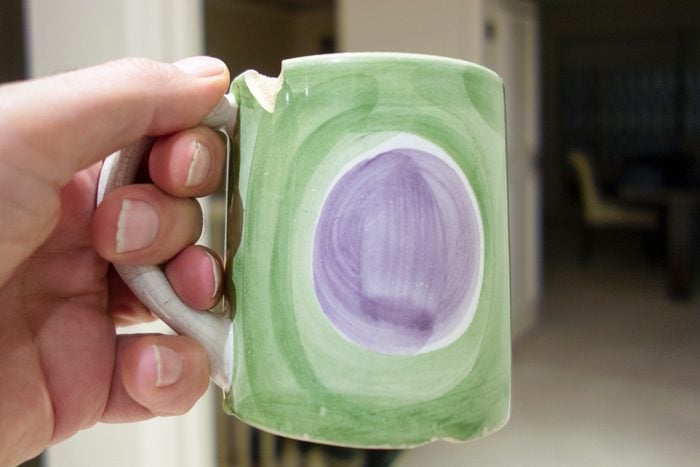 close up of hand holding chipped mug
