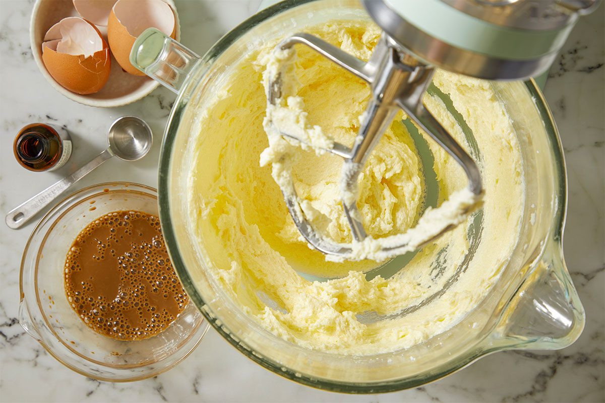 A horizontal overhead image shows butter and sugar being creamed in a mixing bowl with a stand mixer, with eggs, milk, and espresso mixture nearby.