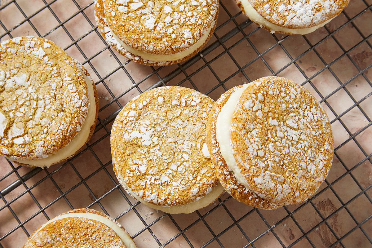 Overhead horizontal push and pulls image of finished crinkle sandwich cookies on cooling rack showing powdered sugar texture.