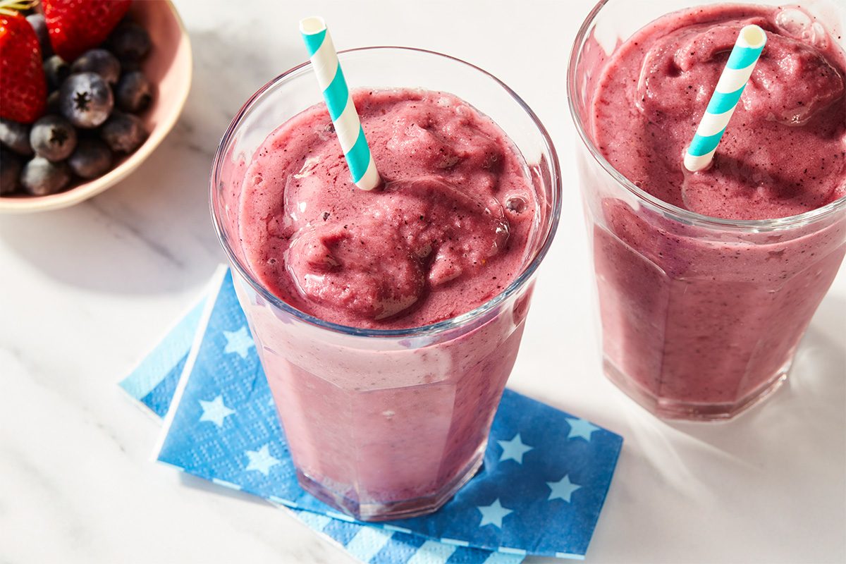 Two berry smoothies served side by side with fresh berries, highlighting a thick and creamy consistency.