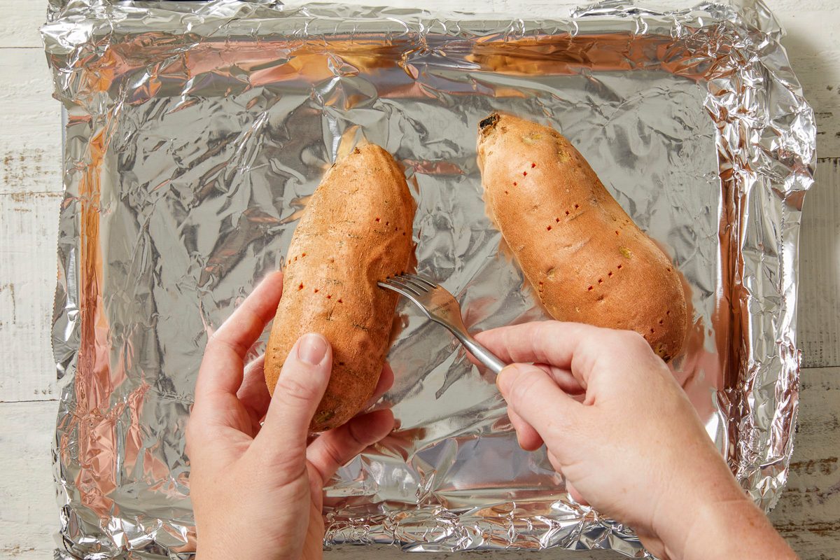 sweet potatoes being pierced with a fork