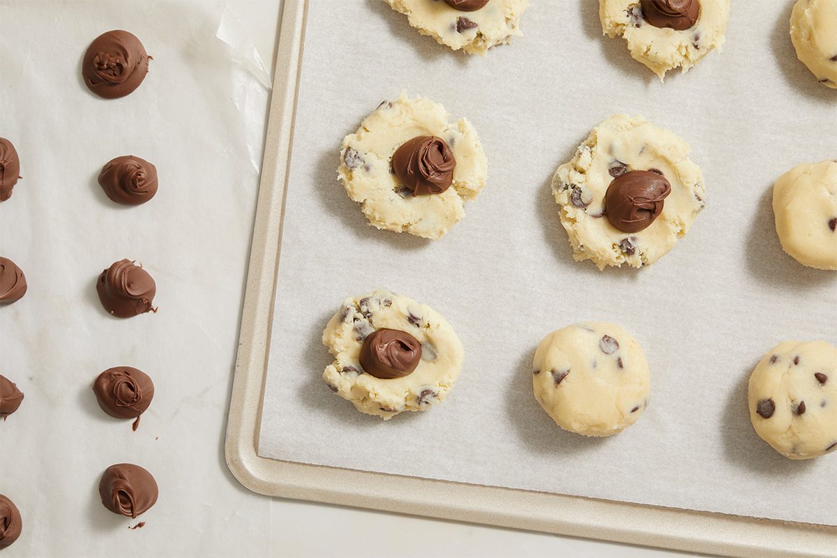 Overhead horizontal image of cookie dough topped with Nutella dollops before baking.