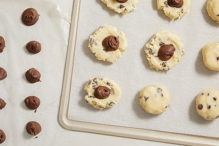 Overhead horizontal image of cookie dough topped with Nutella dollops before baking.