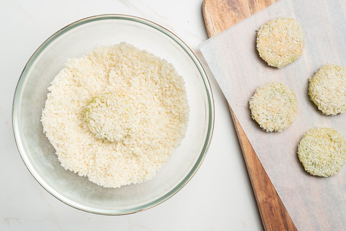 Overhead shot of a coated item with bread crumbs, placed on a towel set over a wooden board
