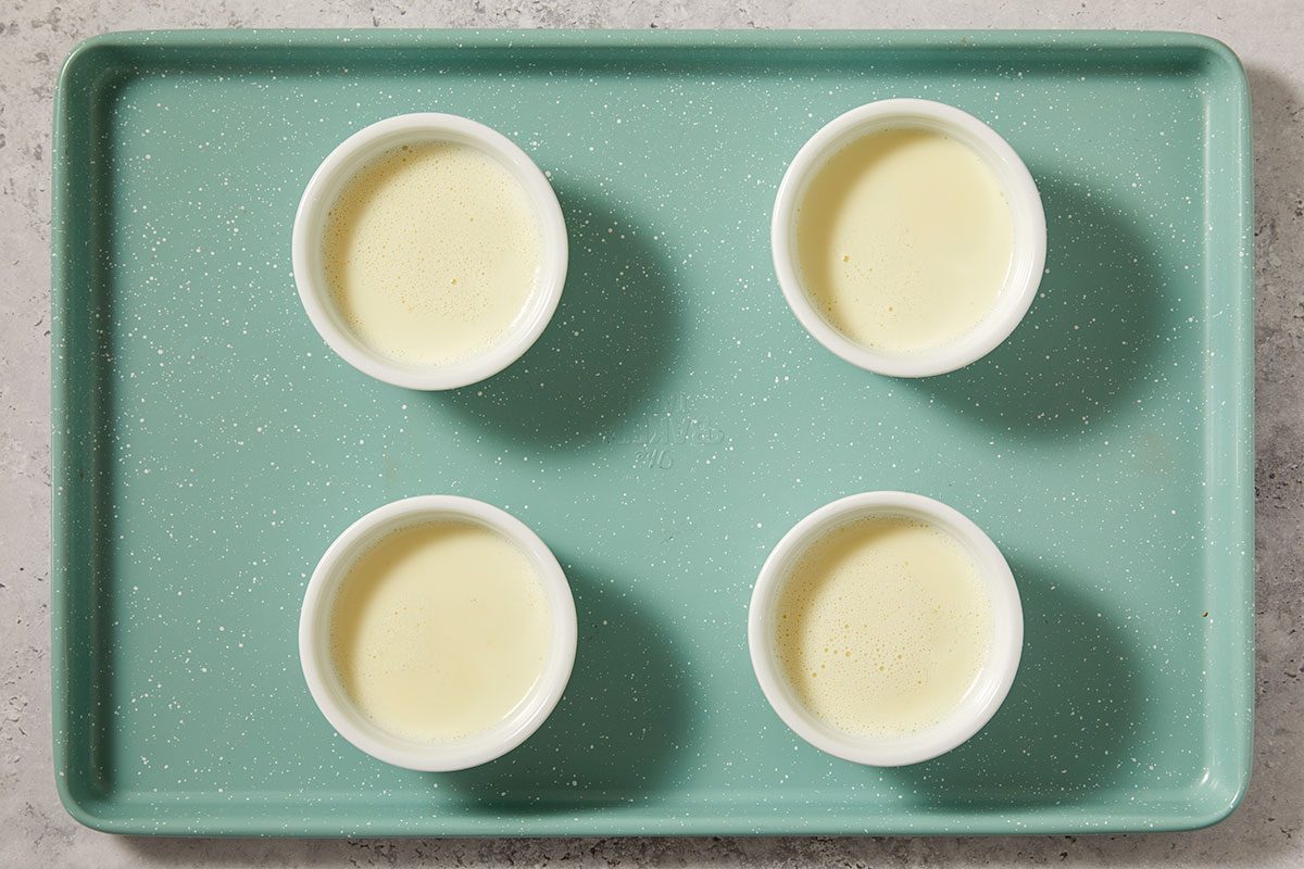 A horizontal overhead image shows four ramekins filled with smooth panna cotta on a tray as the dessert sets.