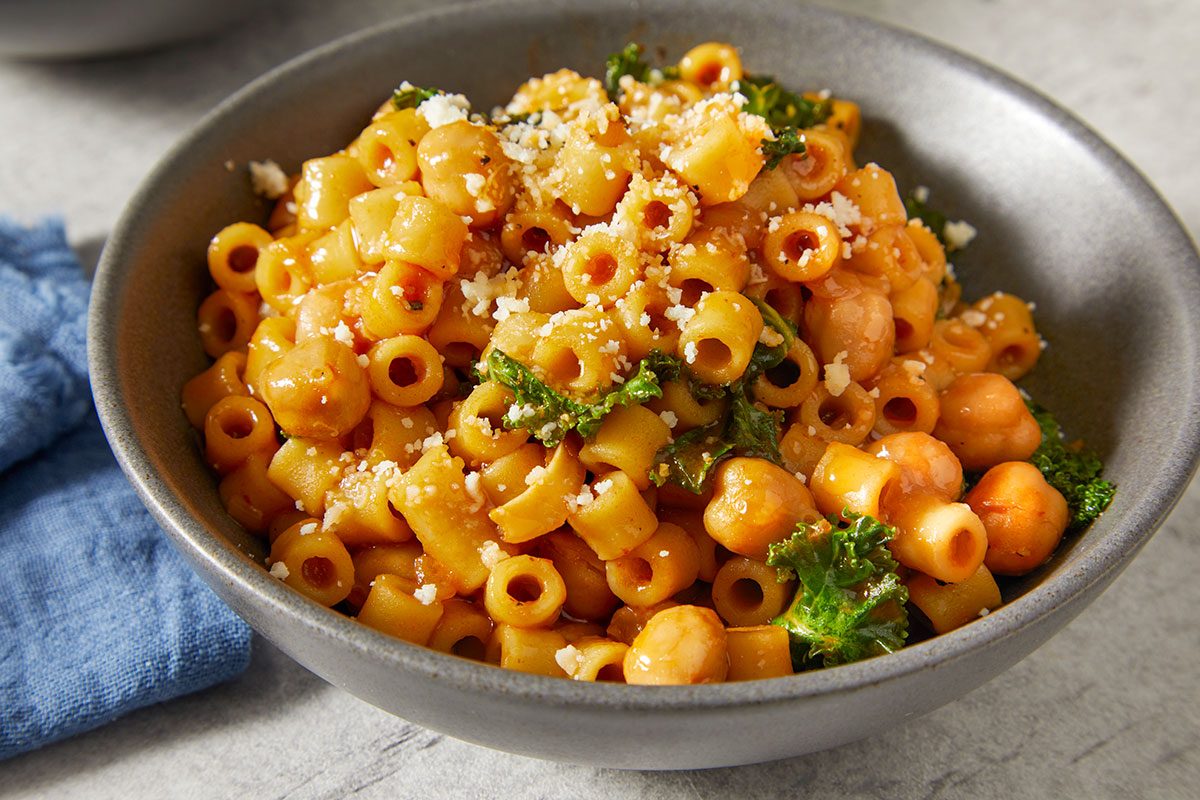 Close-up horizontal image of pasta e ceci in a bowl topped with grated Romano cheese.