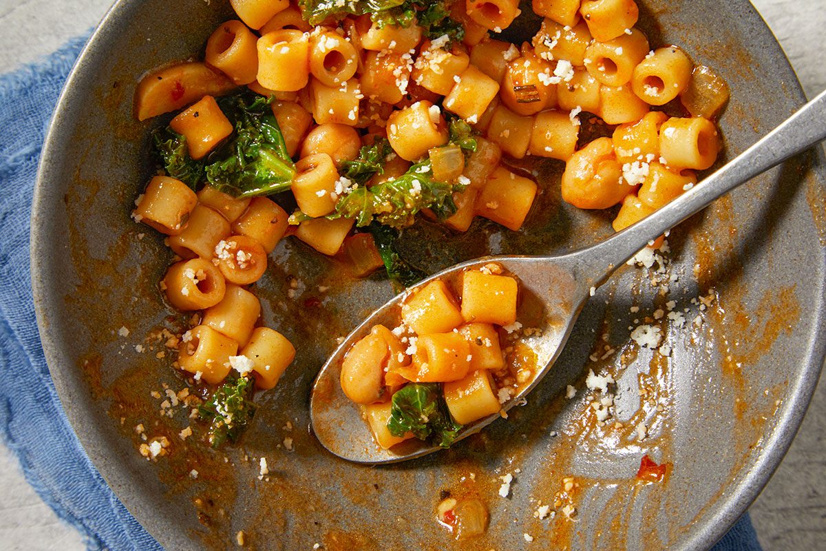 Close-up horizontal image of pasta e ceci partially eaten showing texture of pasta, chickpeas, and broth.