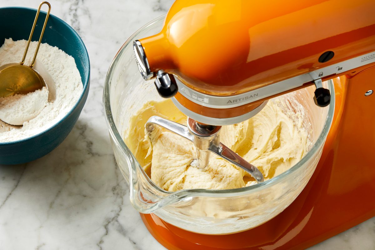 Overhead view of peach cookie dough fully mixed in a stand mixer bowl, showing a smooth, pale dough consistency.