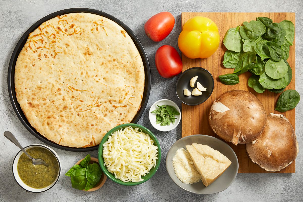 pizza crust, garlic, pesto sauce, cheese, herbs and vegetables