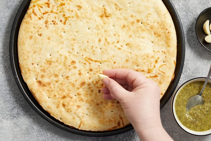 Rubbing the cut sides of the garlic cloves over the pizza crust