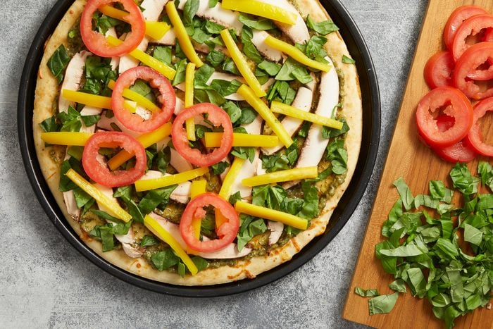 pizza crust topped with spinach, mushrooms, bell pepper, tomatoes and basil