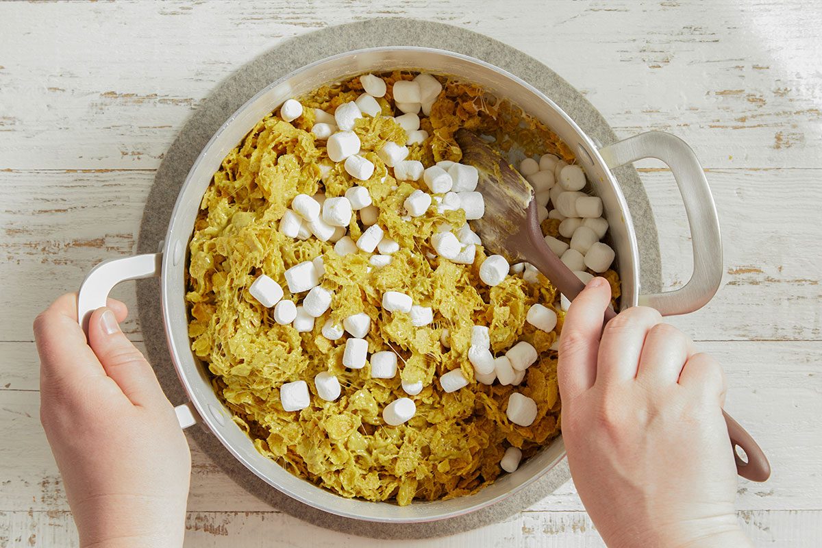 Cornflakes and marshmallows are combined and stirred into the melted mixture to coat evenly.