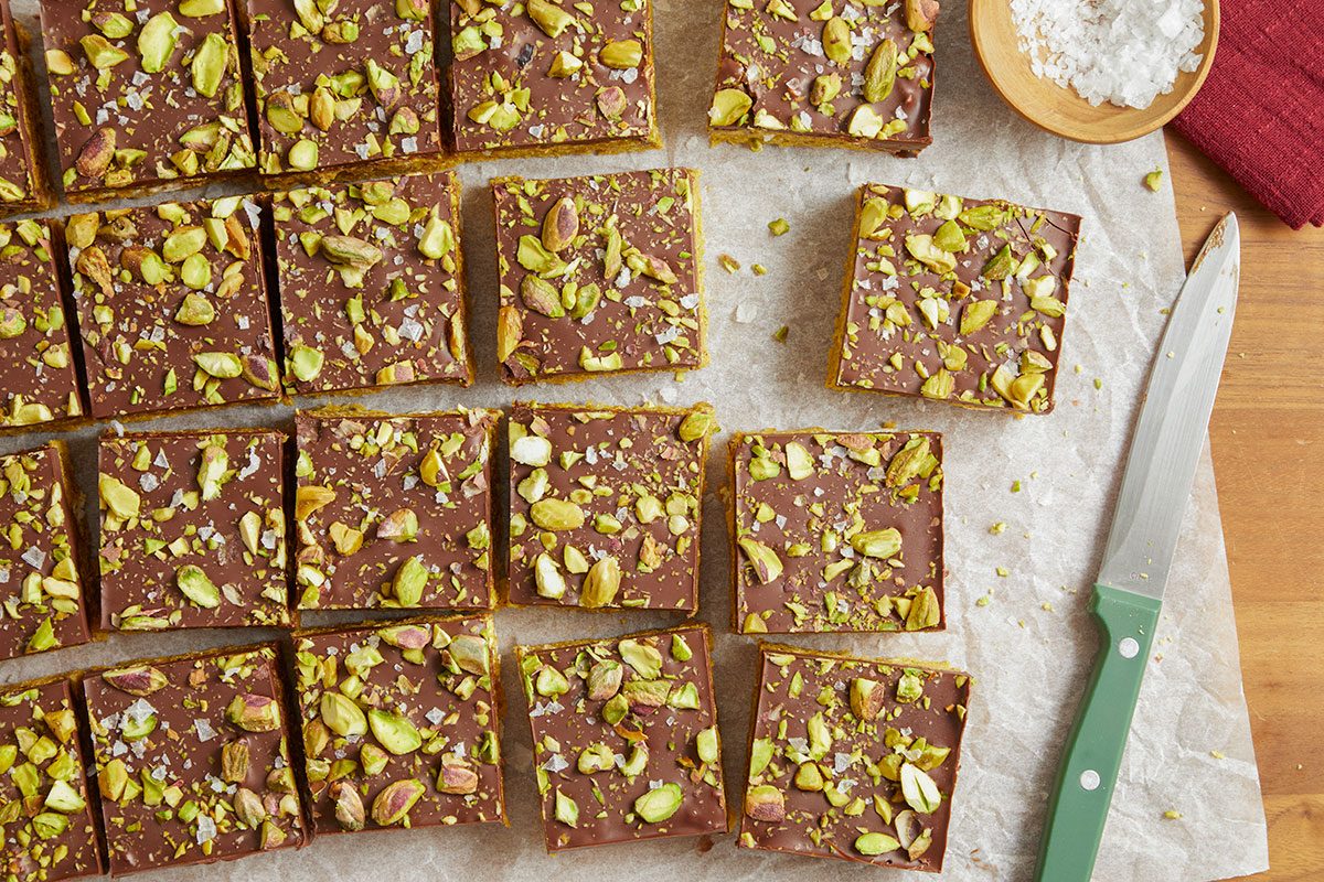 The set bars are cut into even squares and arranged on parchment paper.
