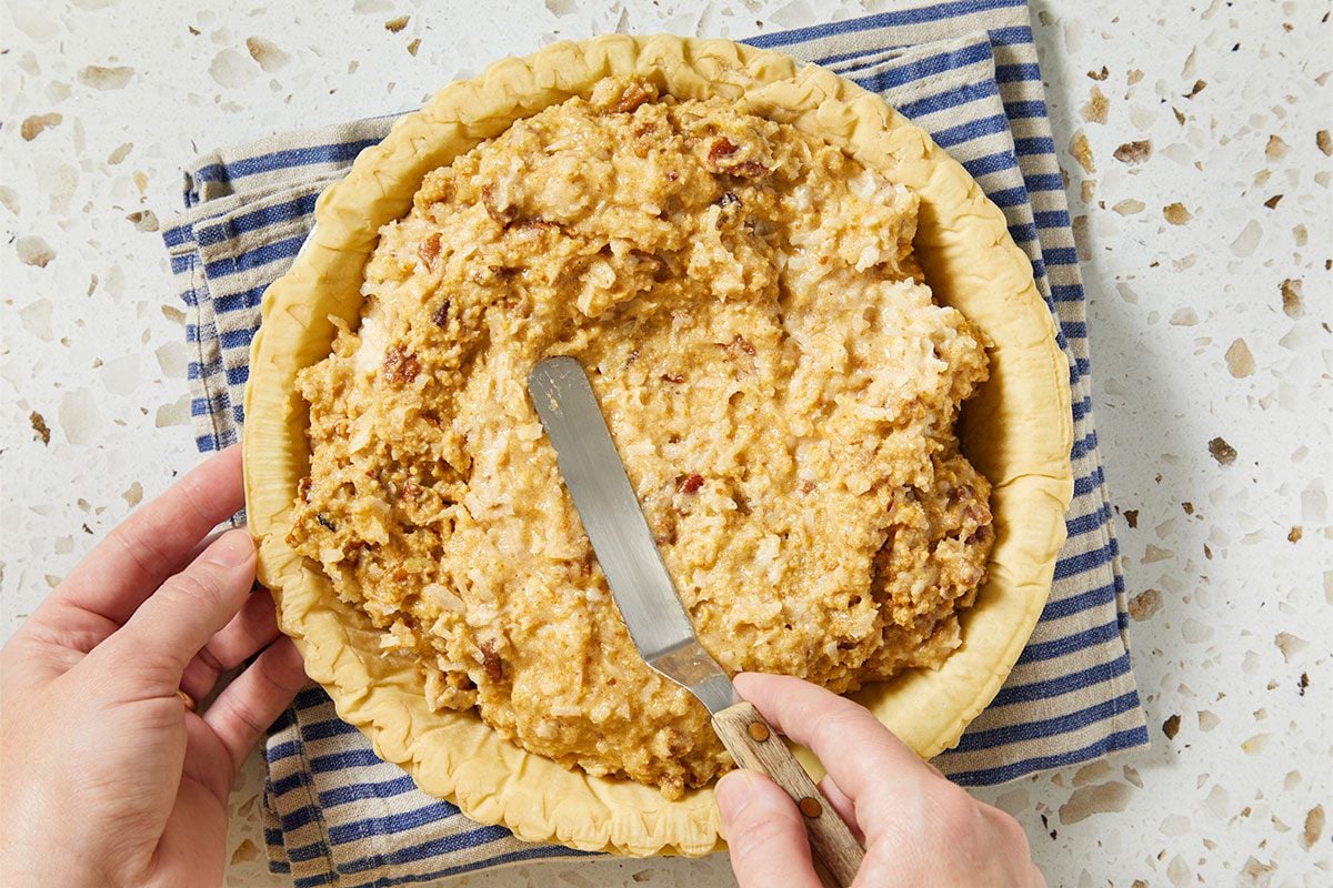 A horizontal overhead image shows the pie filling being spread evenly into a prepared pie crust using a spatula.
