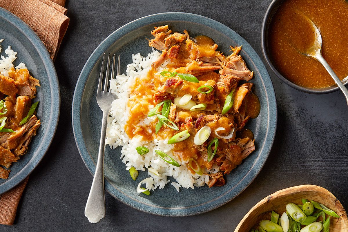 Eye-level horizontal image of plated pork and rice with sauce served in bowls for a finished presentation.