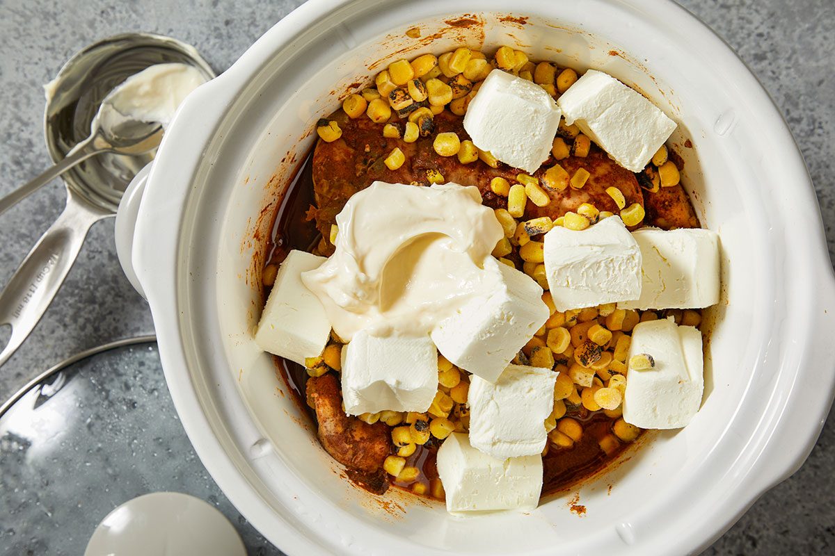 Overhead horizontal step-by-step image of slow cooker filled with chicken, corn mixture, and cubed cream cheese before cooking.