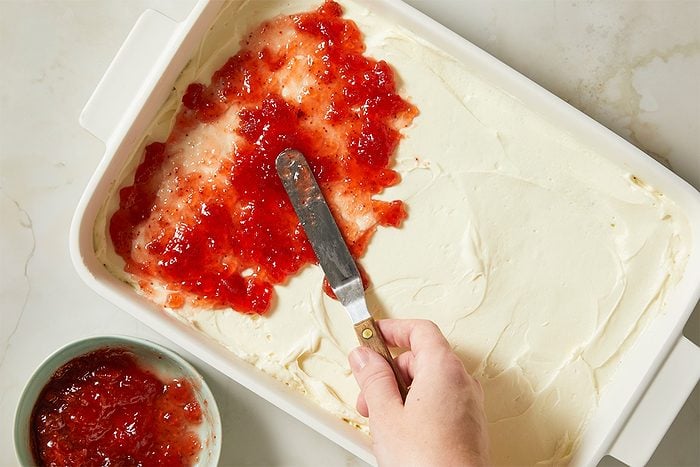 Strawberry preserves are spread across the cream layer to create a sweet fruit layer.