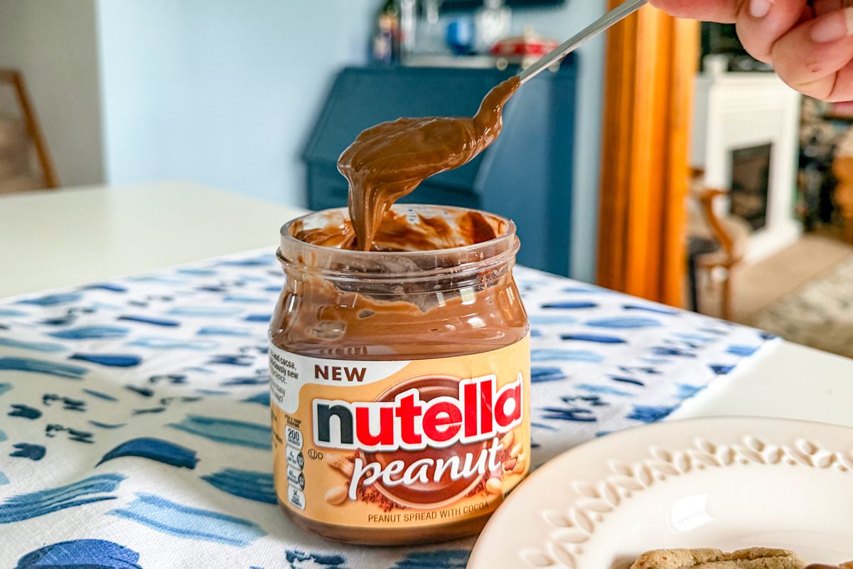 spoonful of Nutella Peanut over jar on a table