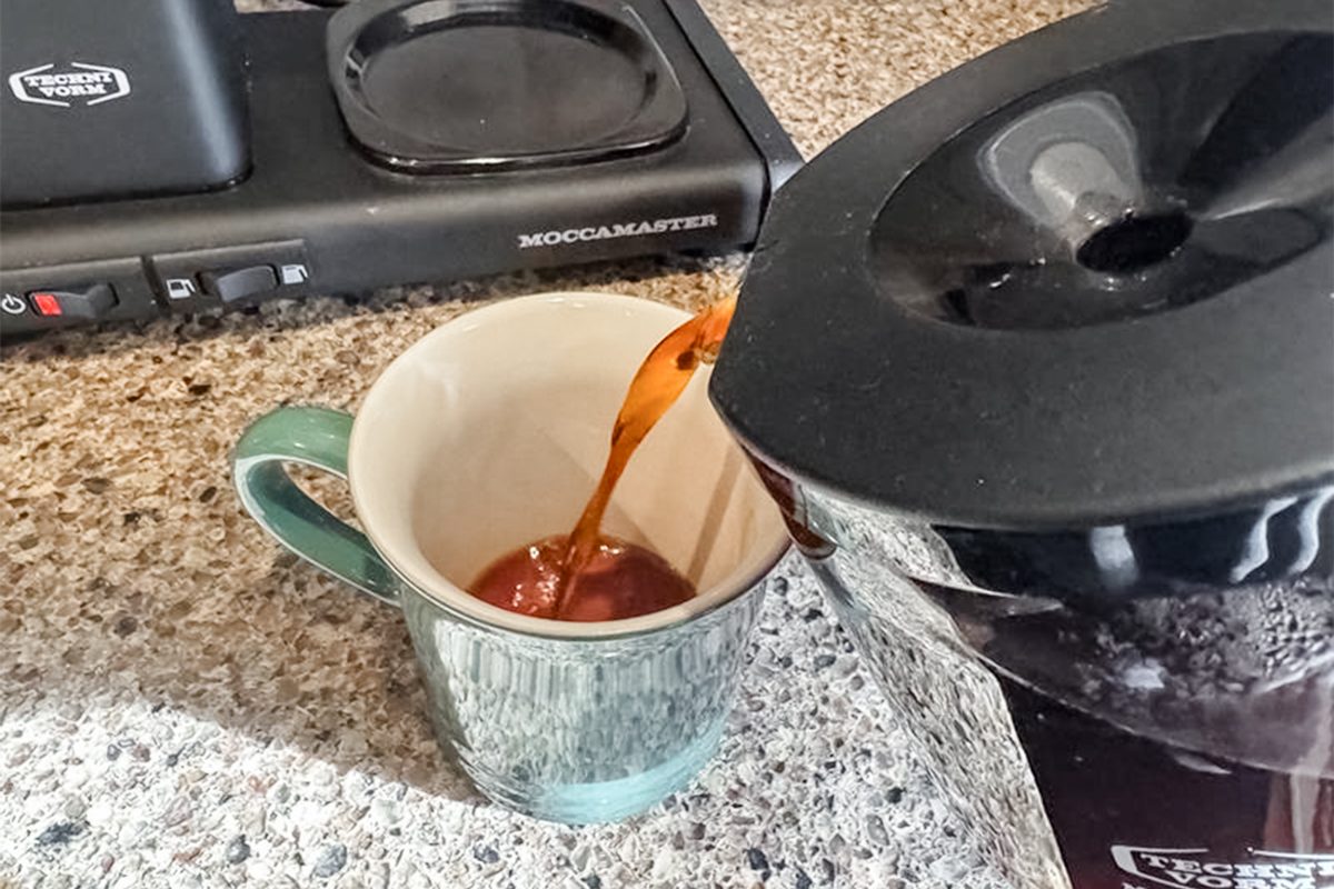 coffee being poured into a mug in front of a coffee maker