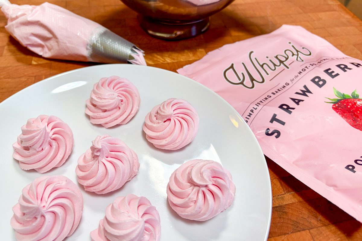 strawberry frosting on a white plate next to Whipzi confectioners sugar