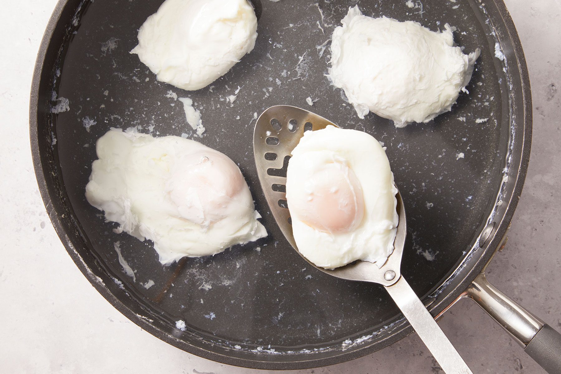 Use a slotted spoon to lift the poached egg out of the water gently