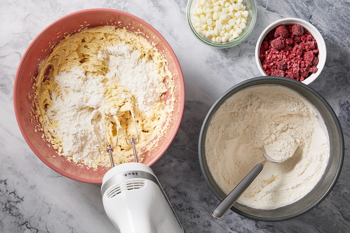 Overhead horizontal image of flour being added to the cookie dough mixture during preparation.