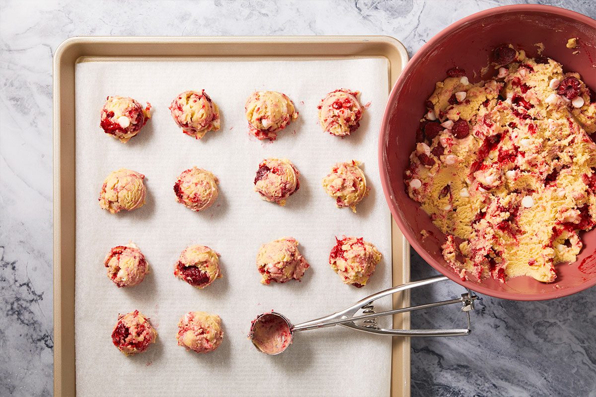 Overhead horizontal image of scooped cookie dough portions placed onto a baking sheet.