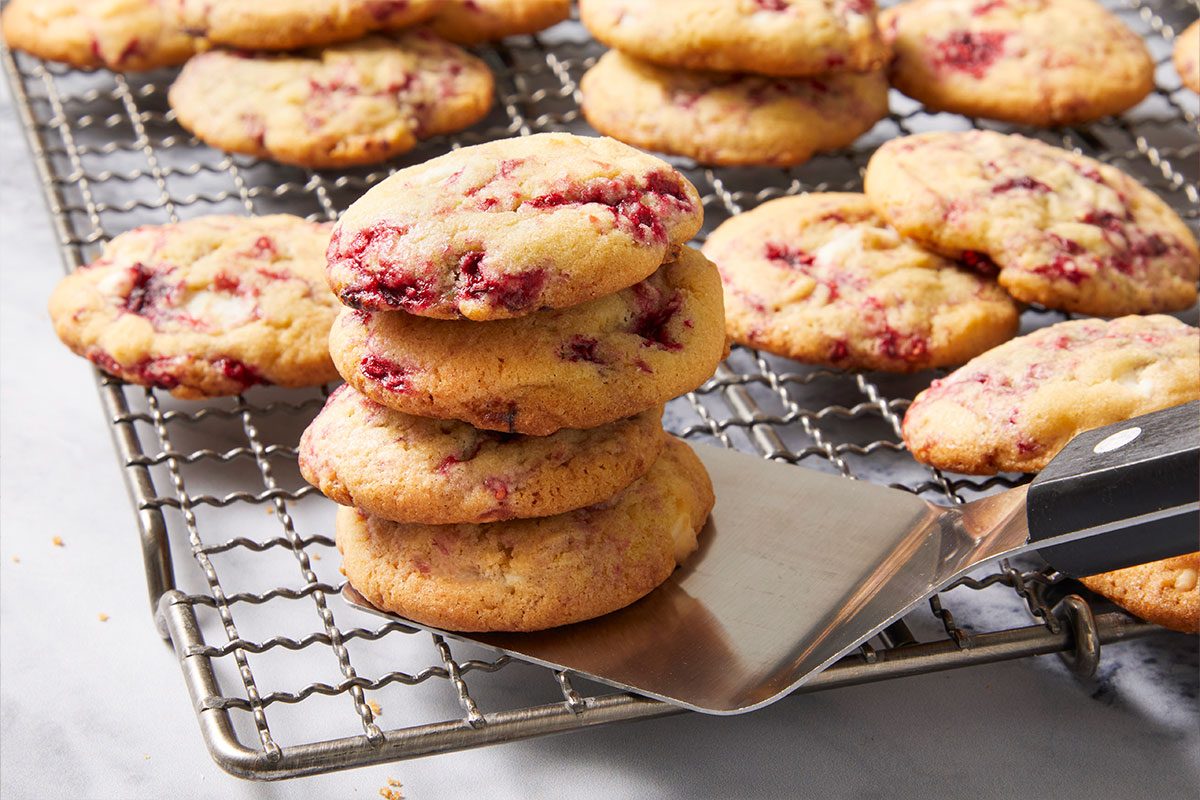 Eye-level horizontal image of stacked cookies on a cooling rack with spatula underneath.