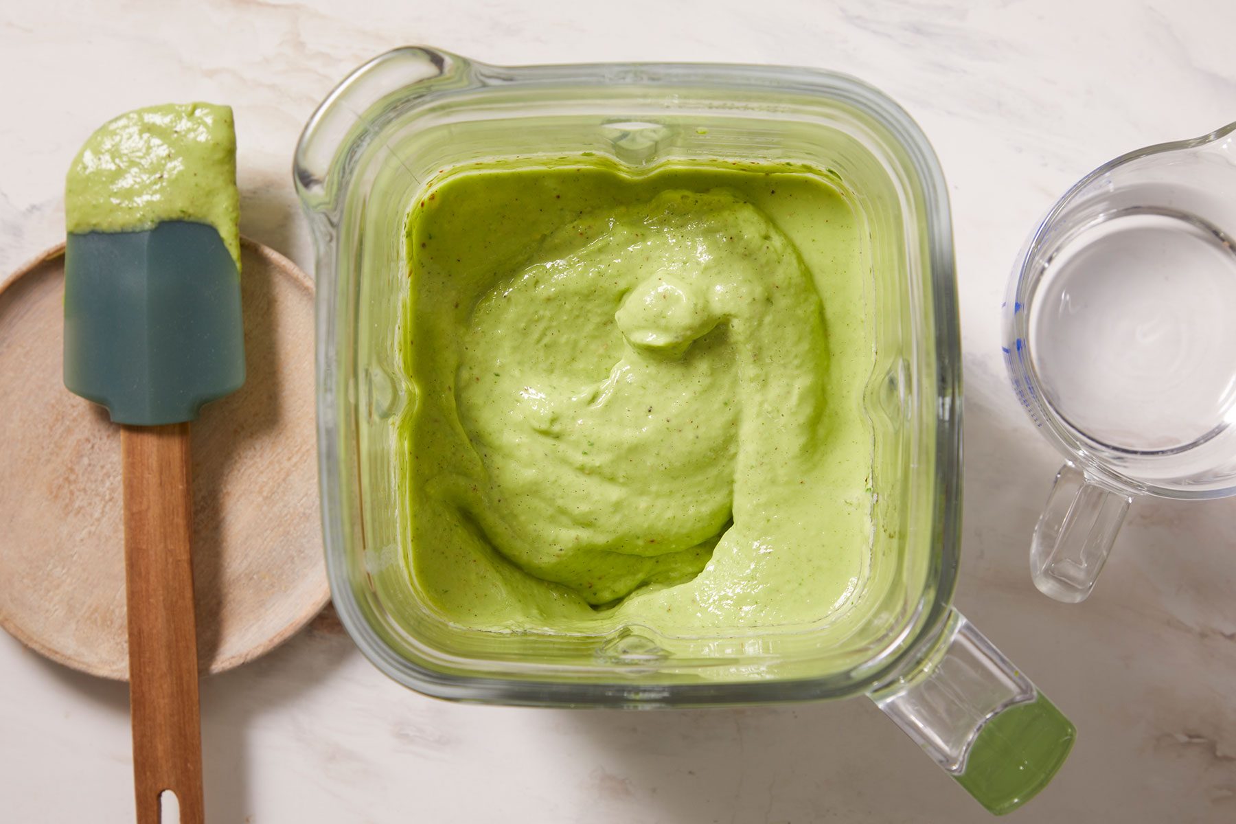 Smooth and creamy blended Avocado basil dressing in a food processor.