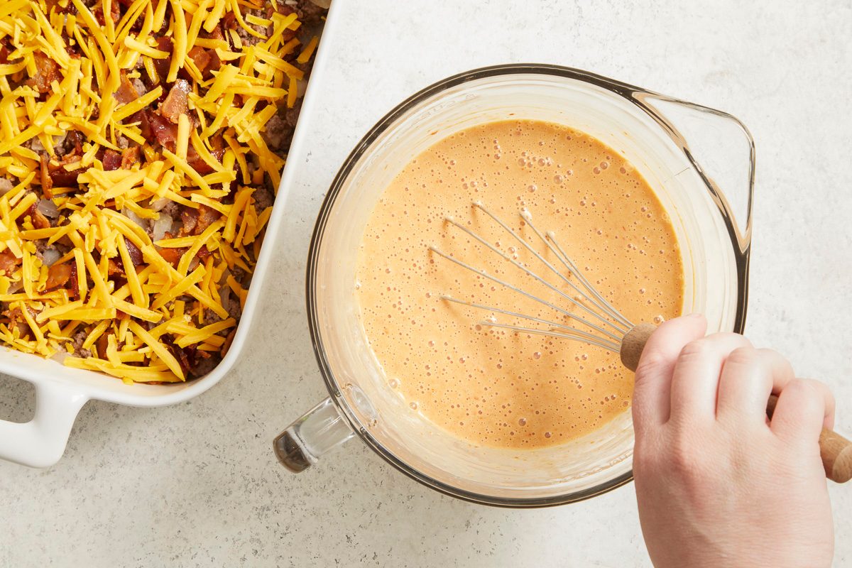 Overhead horizontal step-by-step image of egg and cream mixture being whisked with seasonings for casserole base.