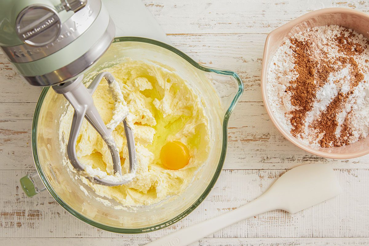 A horizontal image shows butter and sugar being mixed with eggs in a stand mixer to begin the cake batter.