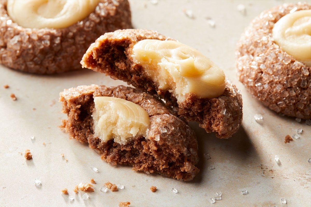 Eye Level horizontal image of a cookie split in half with frosting on top. Two more cookies are in the background and the cookies have sugar sprinkled on them.