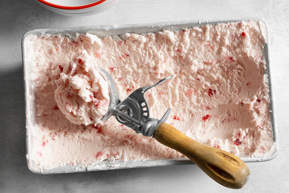 Overhead shot of transfered to freezer containers; ice cream scoop; white marble background;