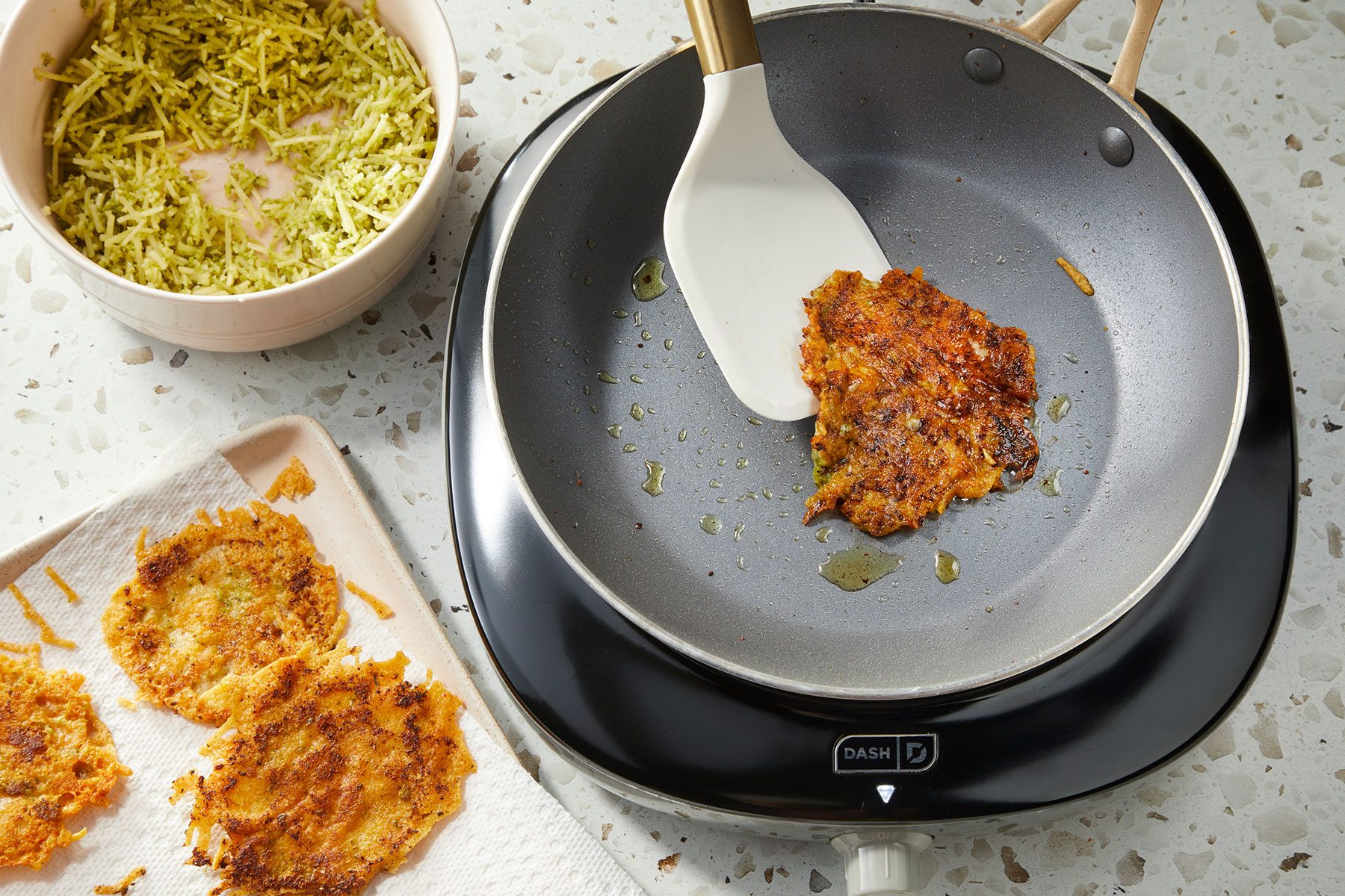 Pesto Parmesan Crisp being cooked on a large skillet and being flipped using a spatula. Some cooked ones placed on side.