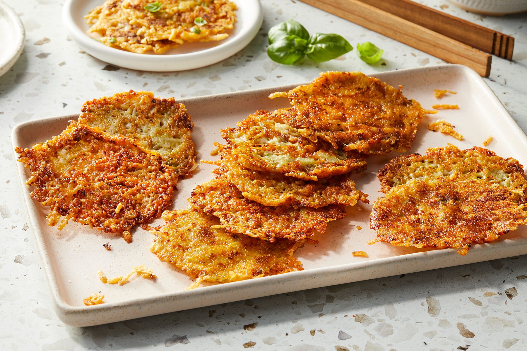 Pesto Parmesan Crisps placed on top on each other and served in a rectangular white tray.