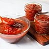 texas barbecue sauce in a large glass bowl next to a chopping board with two small jars of barbecue sauce