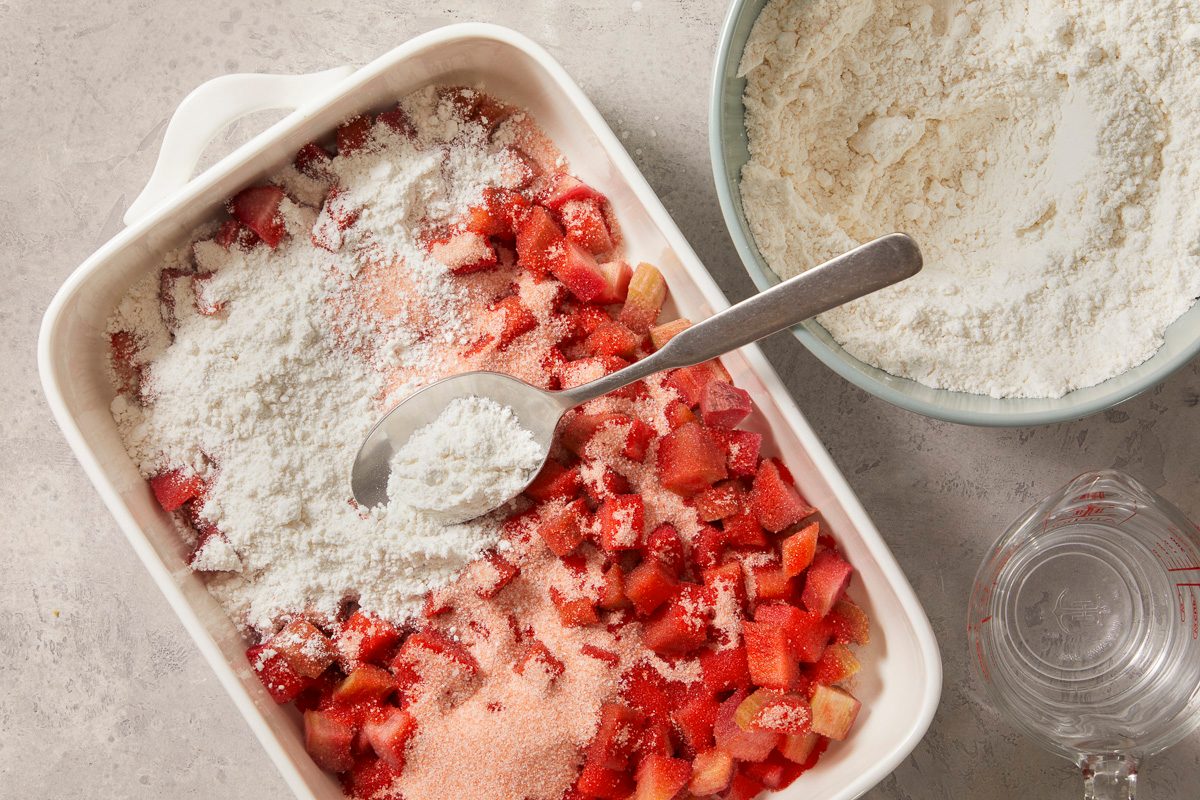 A horizontal overhead image shows dry cake mix being sprinkled over the rhubarb and sugar mixture in a baking dish.
