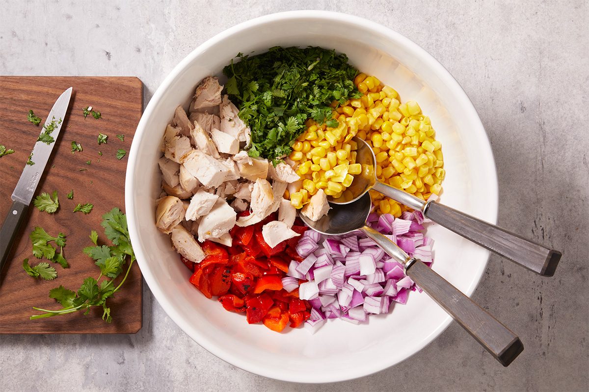 Combine cubed rotisserie chicken, corn, roasted red peppers, chopped onion, and fresh cilantro in a large bowl.