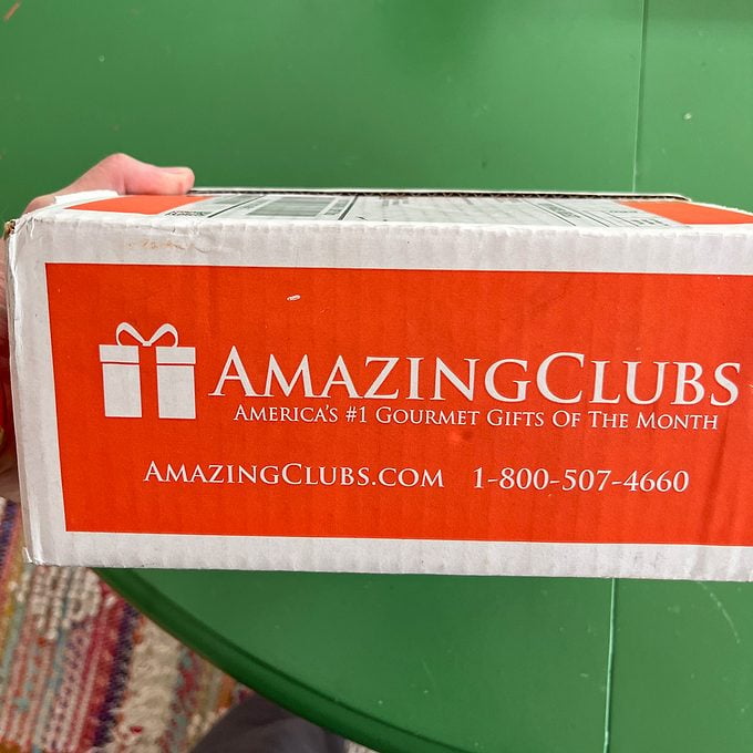 close up of Amazing Clubs box being held in front of a green table