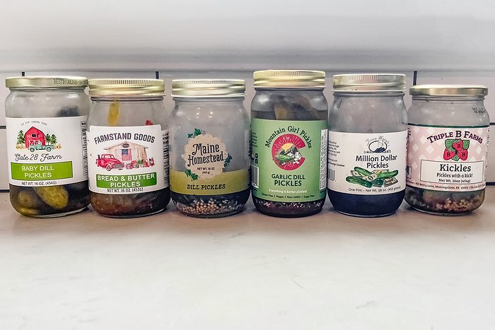 six jars of pickle on a kitchen counter
