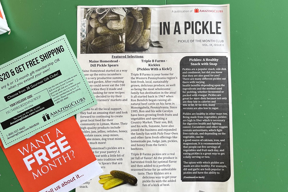 Amazing Clubs Pickle Of The Month Club newsletter on a green table next to coupons