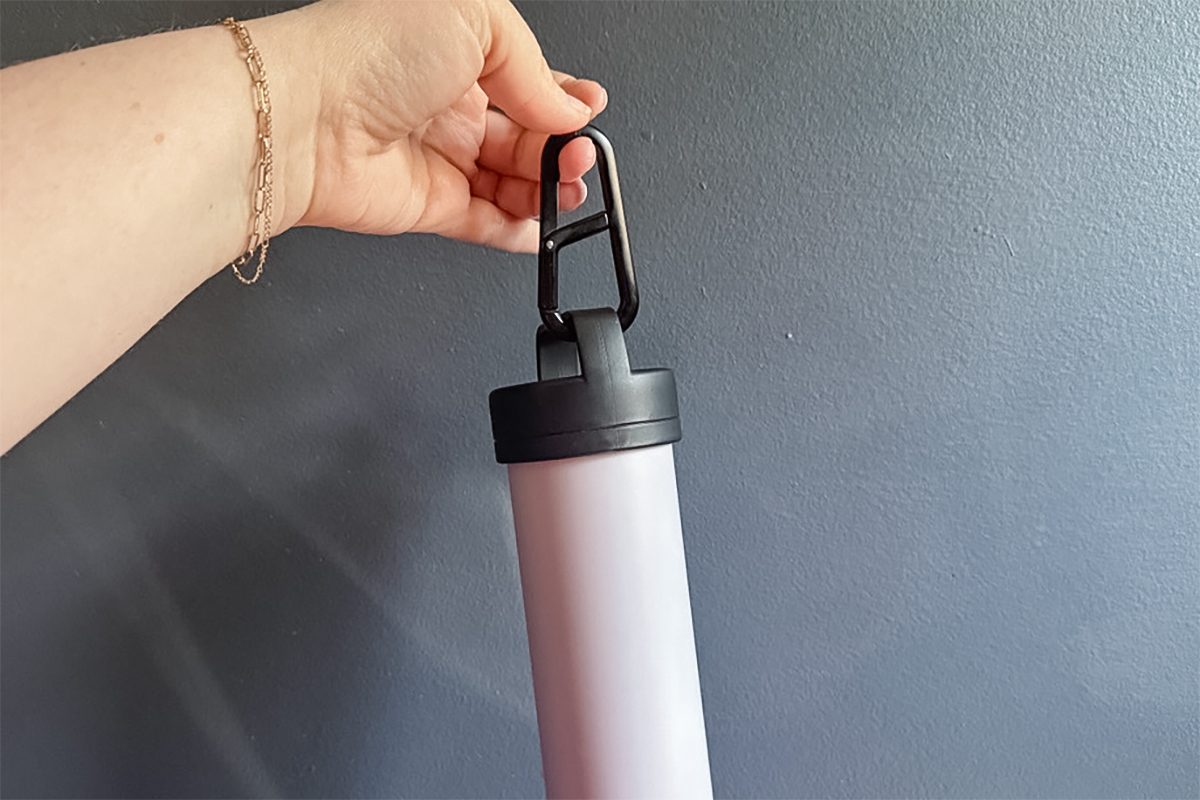 close up of hand holding Espro Travel French Press by the carabiner