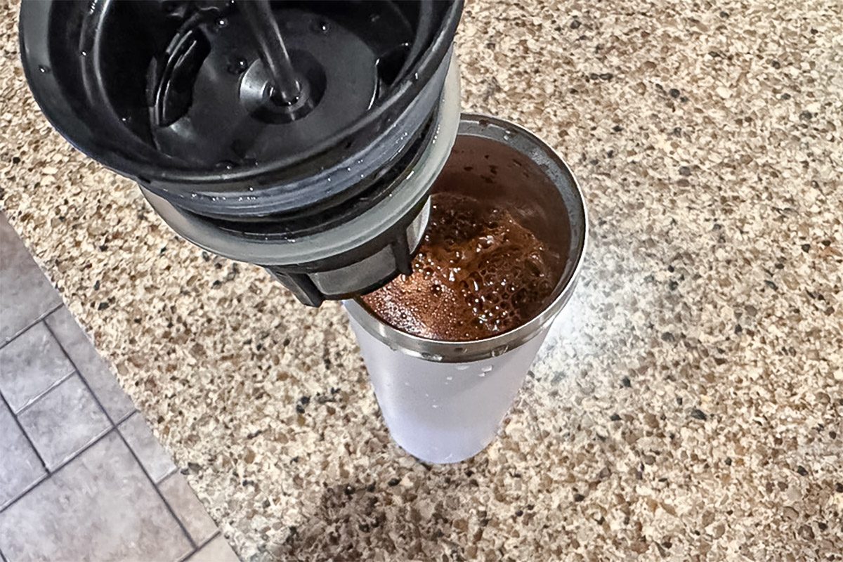 lid with plunger being lowered into Espro Travel French Press containing coffee grounds mixed with water