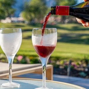 Pouring a glass of Lambrusco wine into a stemless glass