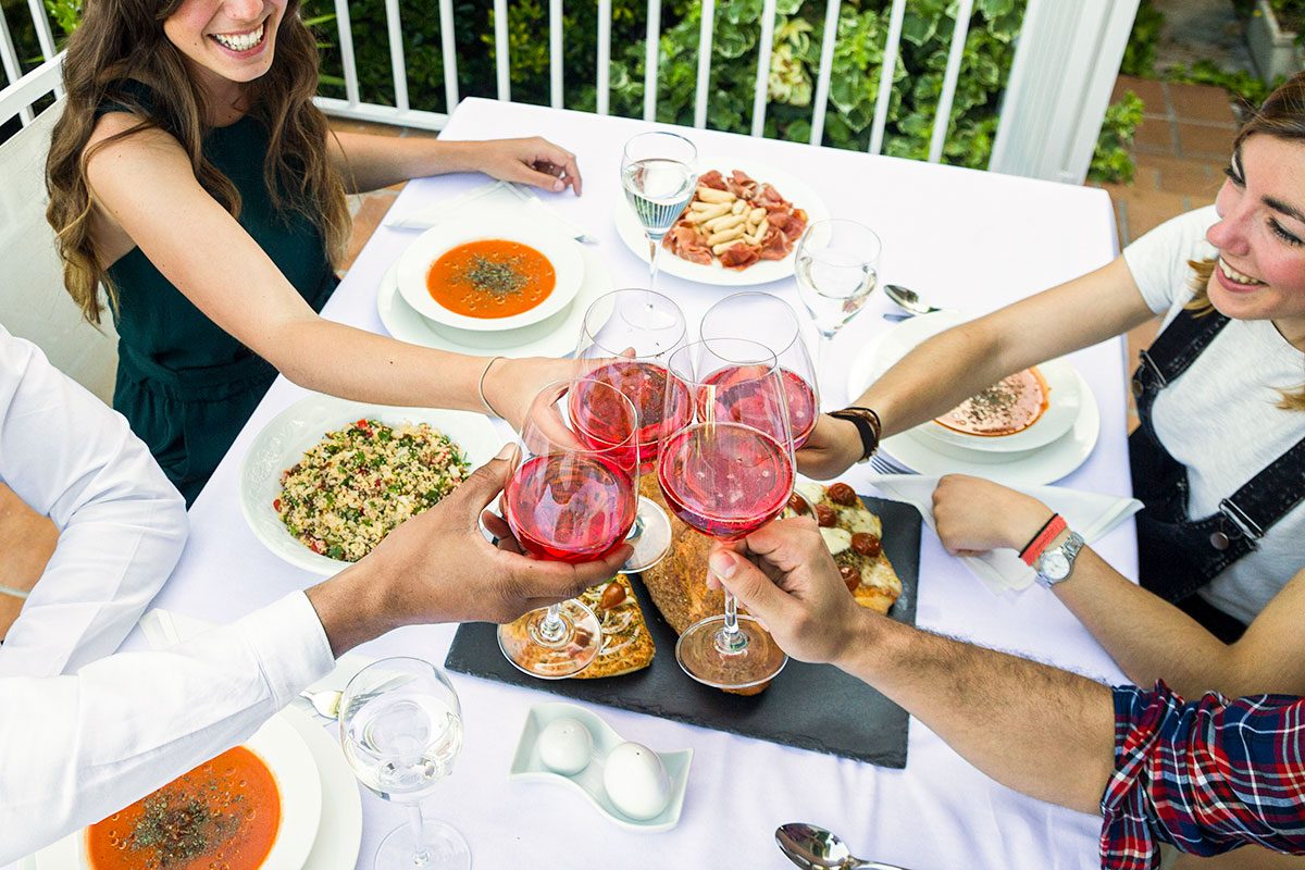 Friends toasting with lambrusco wine during a summer dinner